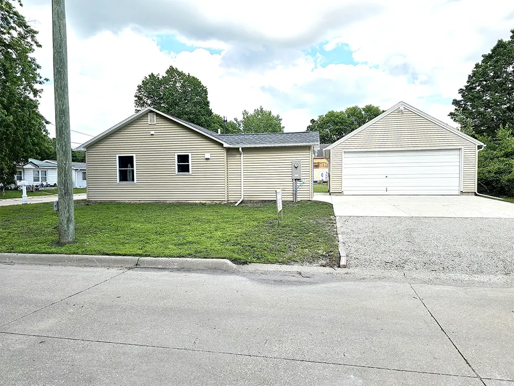 Street view of West side of property showing house with side yard, garage and driveway with breezeway to the private patio area