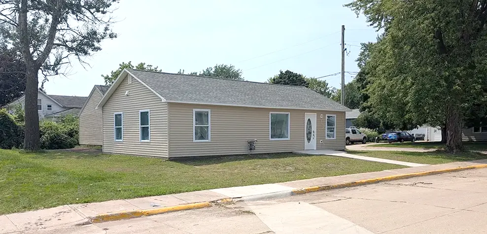 Front exterior of the newly rebuilt home, highlighting the fresh cement work laid over the street-side sewer line replacement.