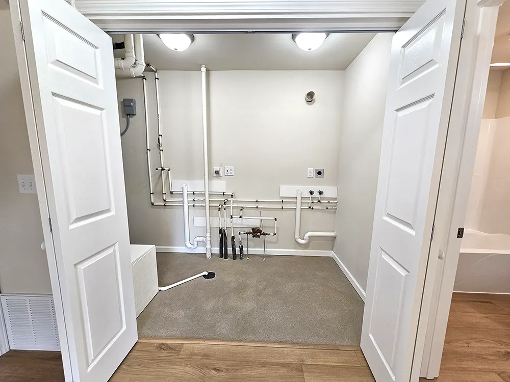 An easily accessible laundry area with plenty of room for a water softener and stacked washer and dryer.